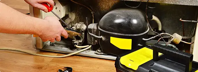 Refrigerator repair technician fixing the compressor and wiring in Villa Park, CA
