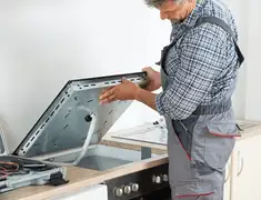 Appliance repair technician installing a built-in cooktop in Irvine, CA