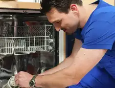 Dishwasher repair technician inspecting and servicing an open dishwasher in Irvine, CA