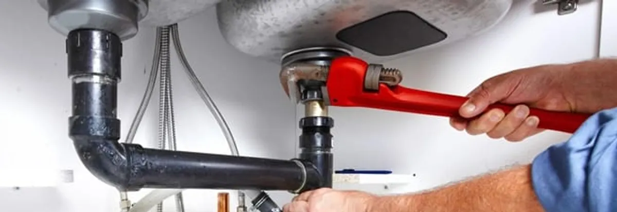 Garbage disposal repair technician tightening the sink drain and disposal connection in Irvine, CA
