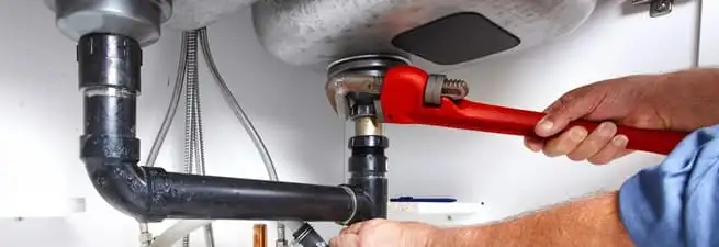 Garbage disposal repair technician tightening the sink drain and disposal connection in Irvine, CA