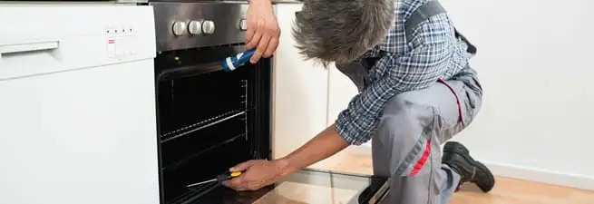 Oven repair technician inspecting and servicing an electric oven in Irvine, CA