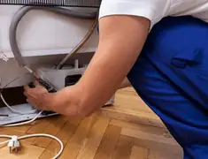 Appliance repair technician fixing refrigerator water line and connections in Irvine, CA