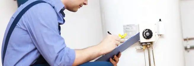 Water heater repair technician inspecting the unit and recording service notes in Irvine, CA